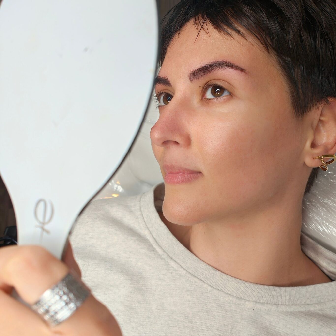 woman watching her eyebrows to the mirror